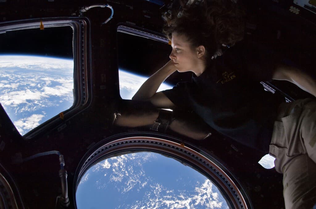 Astronautas observando el espacio a través de una ventana en la estación espacial internacional.